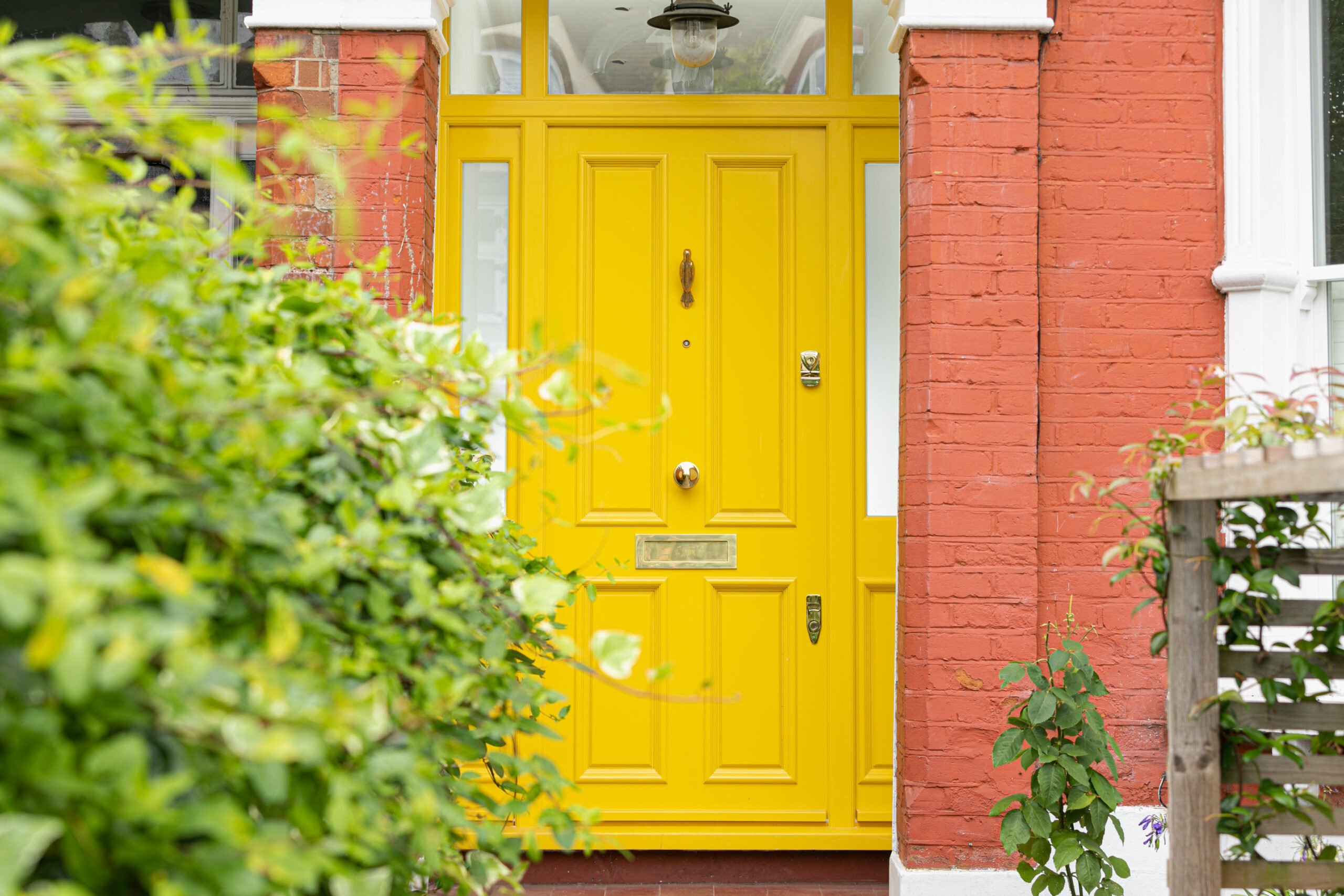 Yellow front door against red brick entrance. Little Greene No 47