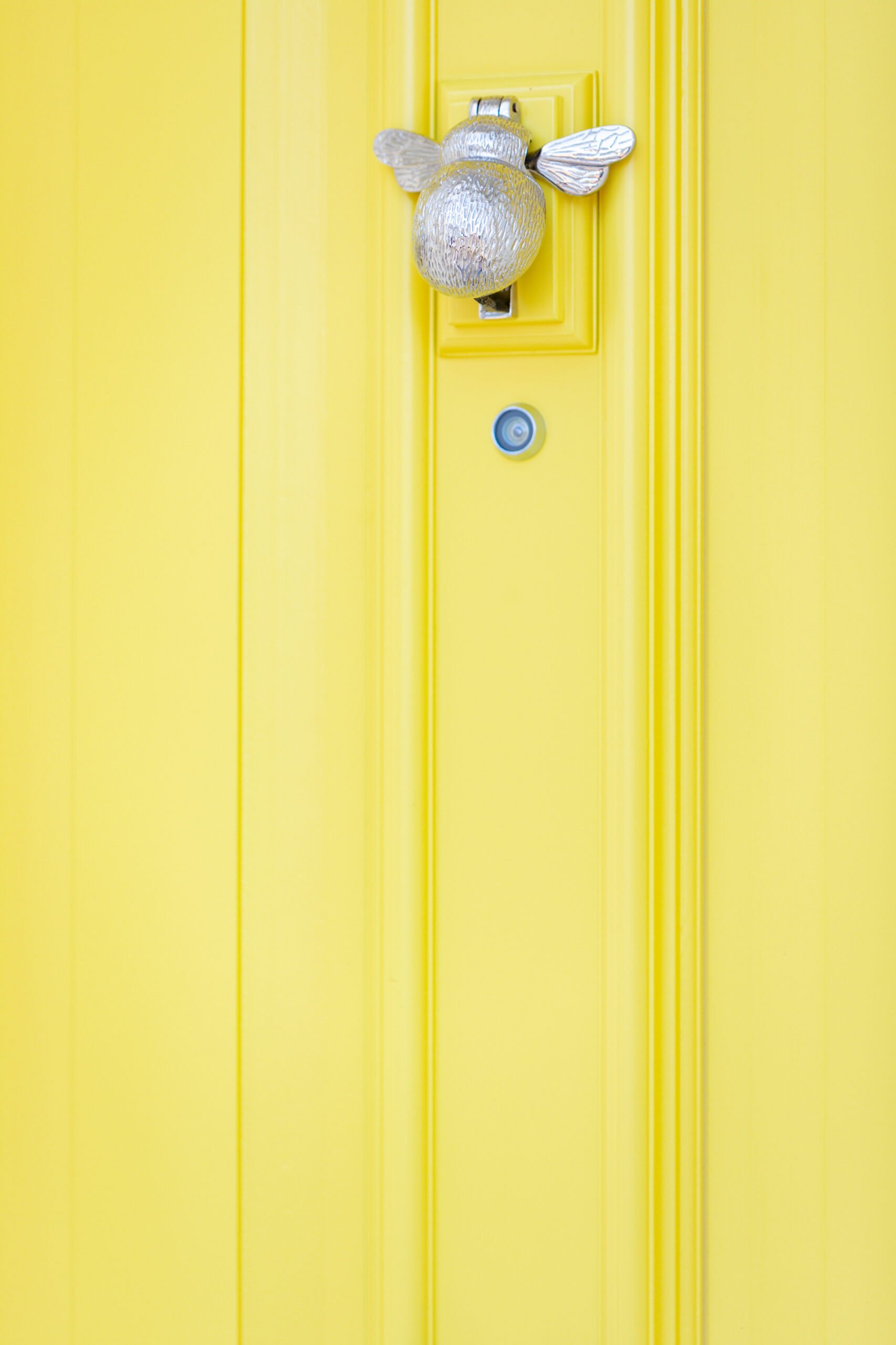 Yellow front door with peephole and ornamentation
