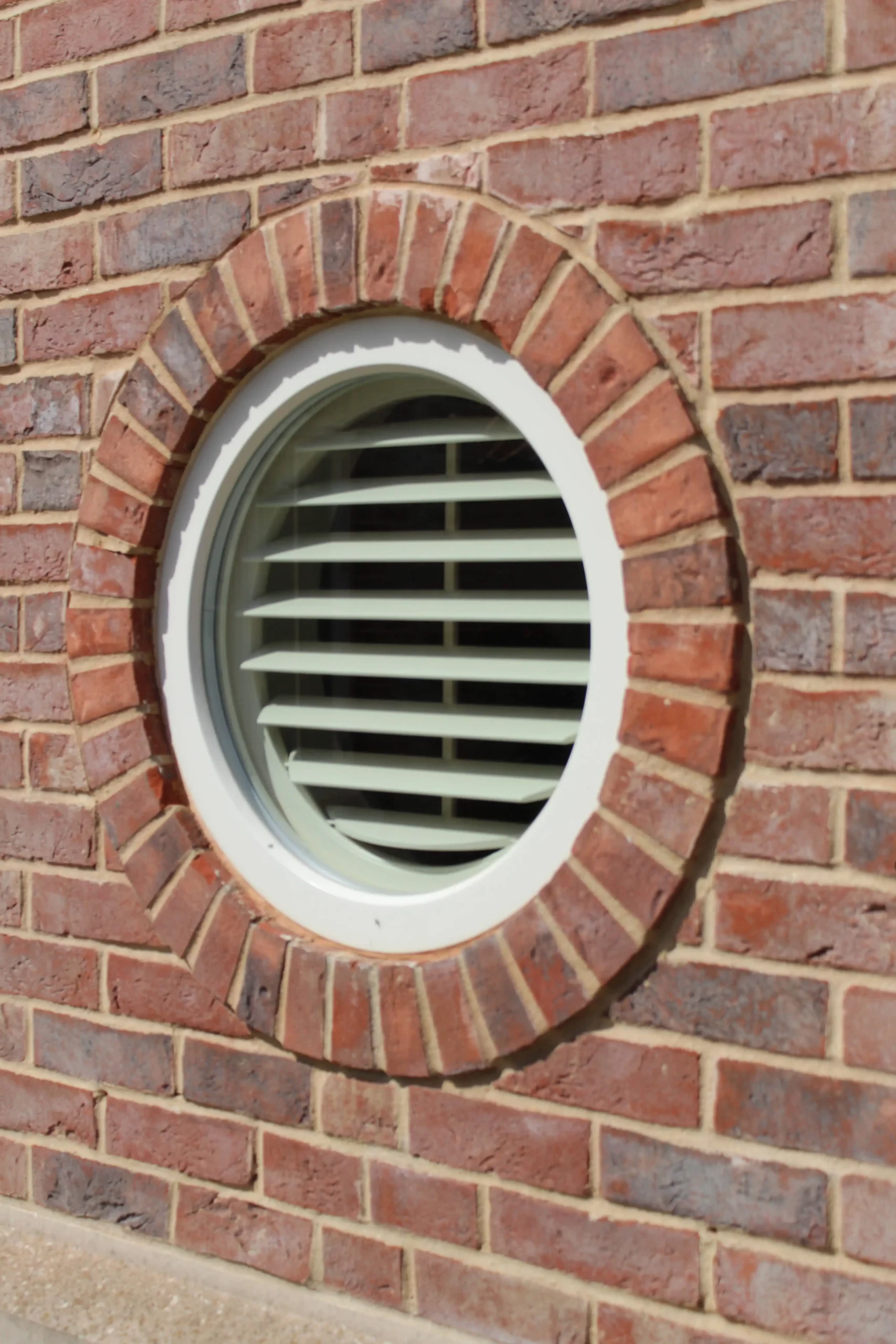 round dormer window in brick wall